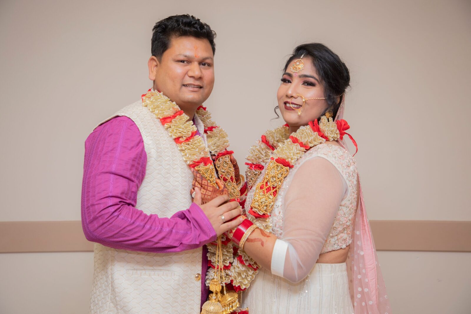 Beautiful couple in traditional attire exchanging wedding vows indoors.